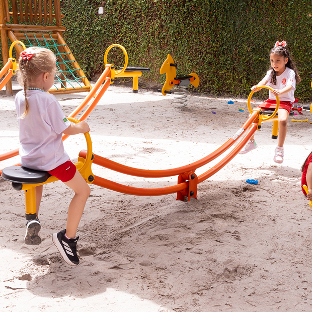 crianças brincando na gangorra em um parque com areia.