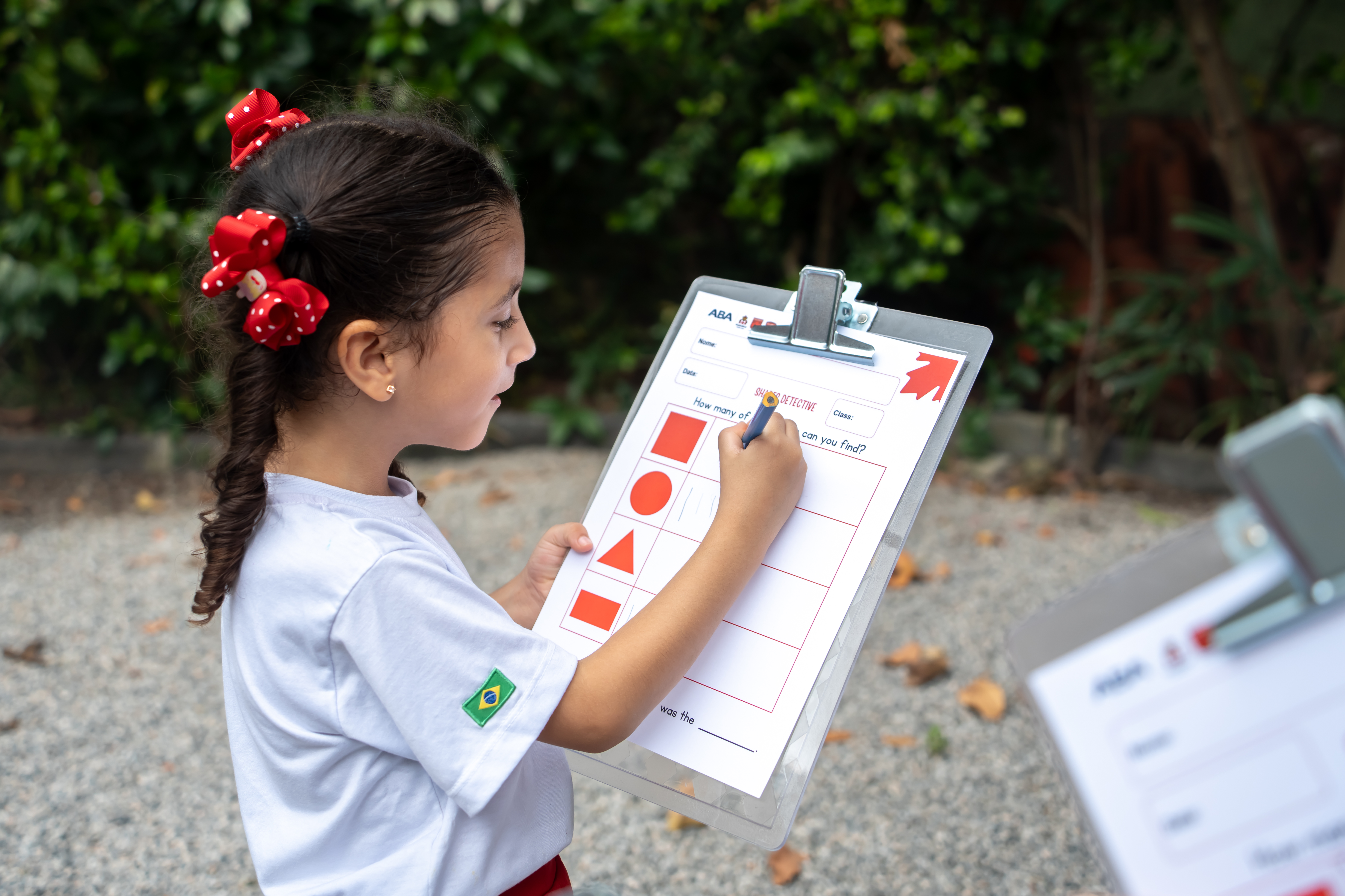 Criança pequena, vestindo uniforme escolar, toca um xilofone colorido no playground da escola