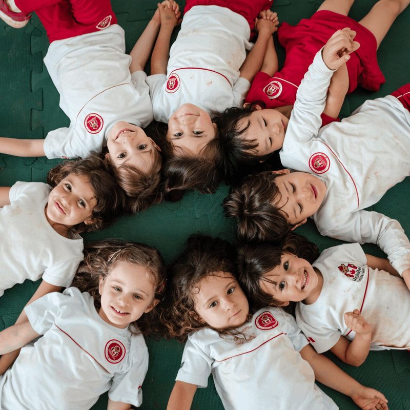 Alunos felizes da Maple Bear, deitados no chao.